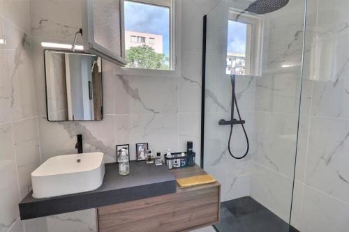 une salle de bain blanche avec un lavabo et une douche dans l'établissement Charmant T2 avec balcon - Parking, AC, Wifi, à Ajaccio