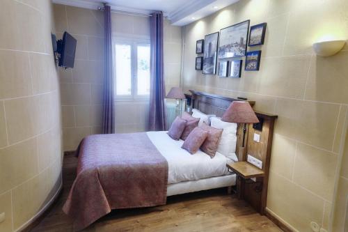 a bedroom with a bed with white sheets and pillows at Hôtel du Château in Vincennes