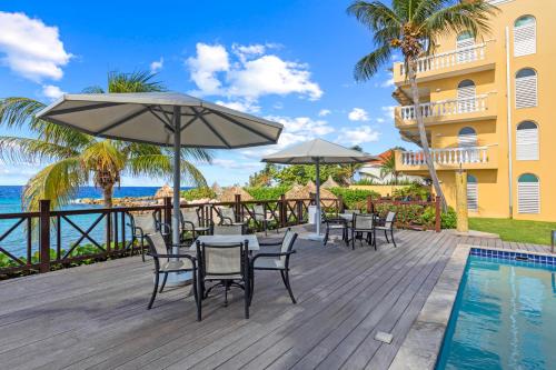 a deck with chairs and umbrellas next to a resort at Beau Rivage 1 in Willemstad