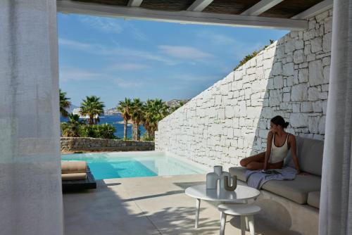 a woman sitting on a couch next to a pool at Mykonos Earth Suites in Mýkonos City