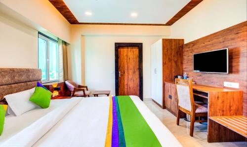 a bedroom with a bed and a desk and a television at Opulence Inn - 500 Meters From Railway Station in Udaipur