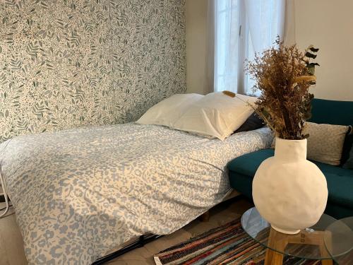 - une chambre avec un lit et un vase sur une table dans l'établissement Studio centre Paris calme cosy, à Paris
