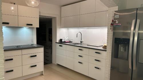 a kitchen with white cabinets and a stainless steel refrigerator at Ferienhaus Achterhus für Familien & Homeoffice in Ratekau