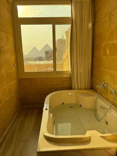 a bath tub in a bathroom with a window at Mirage pyramids view hotel in Cairo