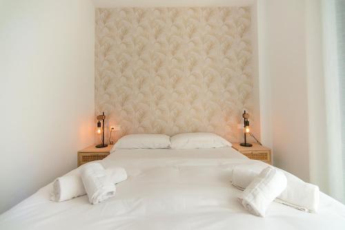 una camera da letto con un grande letto bianco con due lampade di WELCS APARTAMENTO 189 PDA con piscina comunitaria a S'Agaró