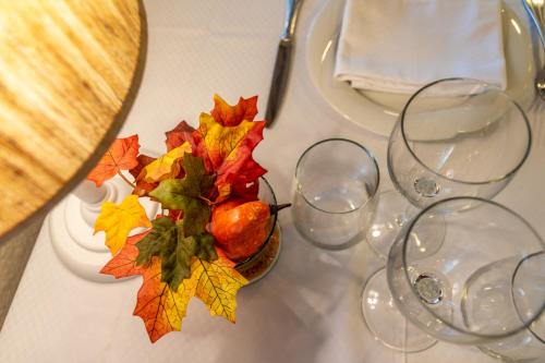 a table with glasses and a vase with autumn leaves at Hotel Esteba in Caldes de Malavella