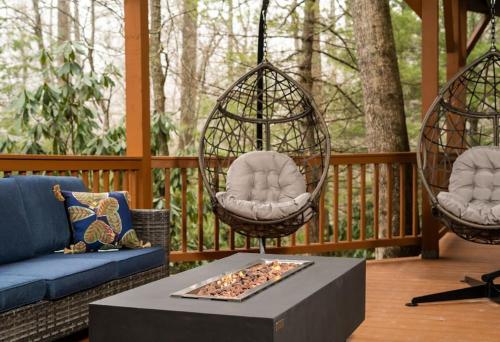 a porch with two swing chairs and a table at Wrap-Around Porch, Hot Tub and Game Room in Blowing Rock