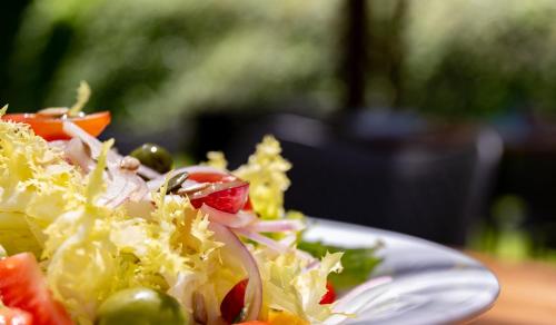 a plate of salad with vegetables on a table at Hotel Esteba in Caldes de Malavella