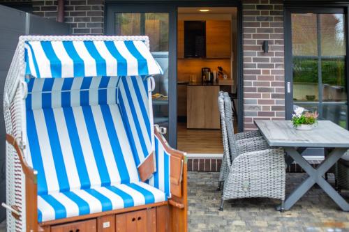 a pair of chairs and a table with a striped umbrella at Winkelschiffchen III mit Sauna in Juist