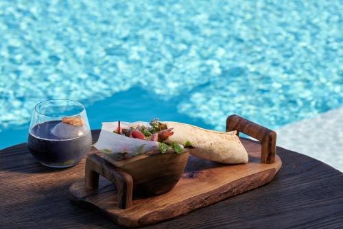 a wooden table with a bowl of food and a glass of wine at Mykonos Earth Suites in Mýkonos City
