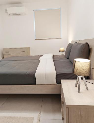 a bedroom with a large bed and a table with a lamp at Blue Pearl in Żurrieq