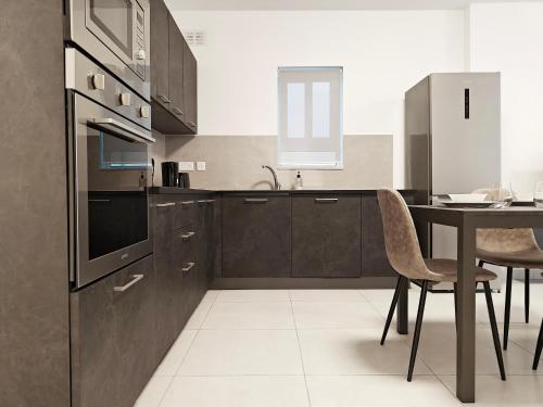 a kitchen with brown cabinets and a table with chairs at Blue Pearl in Żurrieq