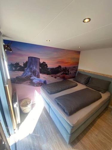 a bedroom with a bed with a painting on the wall at Prachtig Boschalet met CV, Airco en Sauna op de Veluwe in Doornspijk