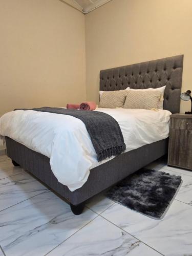 a bedroom with a large bed with a gray headboard at 55 New Street, Makhanda in Grahamstown