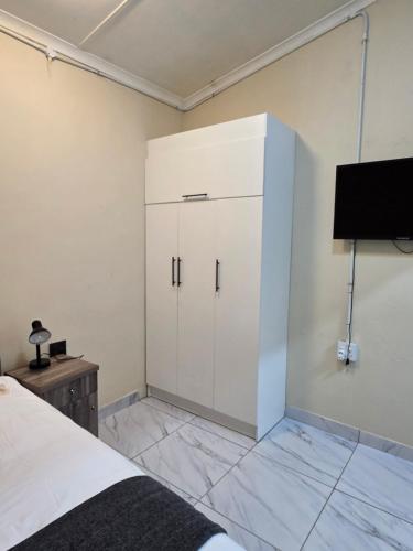 a bedroom with a white cabinet and a tv at 55 New Street, Makhanda in Grahamstown
