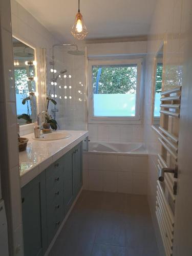 une salle de bain blanche avec un lavabo et une fenêtre dans l'établissement Appartement spacieux, à 20 min de gare St Lazare, à Asnières-sur-Seine