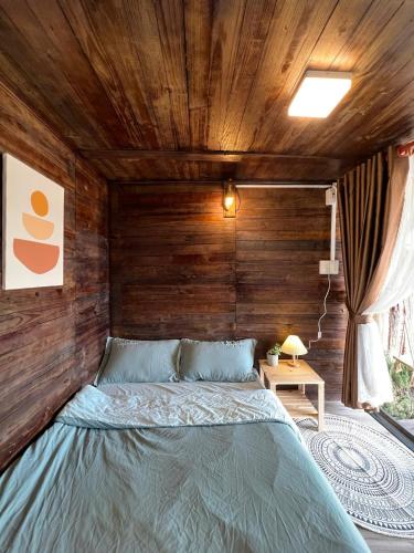 a bed in a room with a wooden ceiling at Nhà Chạng Vạng in Ấp Ða Lợi