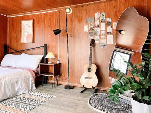 a bedroom with a guitar and a bed and a guitarophone at Nhà Chạng Vạng in Ấp Ða Lợi