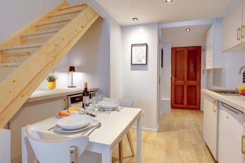 une cuisine et une salle à manger avec une table et des chaises blanches dans l'établissement Bluestay 252 - Duplex au cœur de Paris, à Paris
