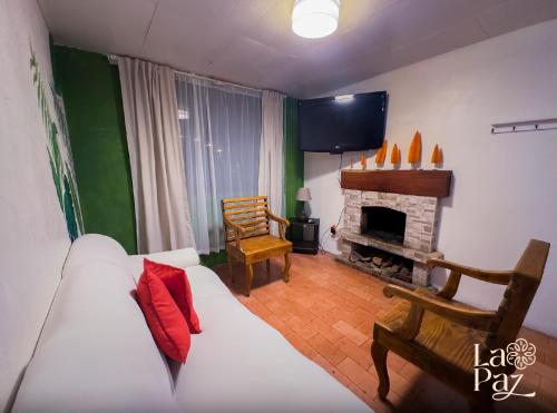a living room with a white couch and a fireplace at Hotel La Paz in Poasito
