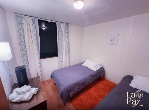 a room with two beds and a table and a television at Hotel La Paz in Poasito