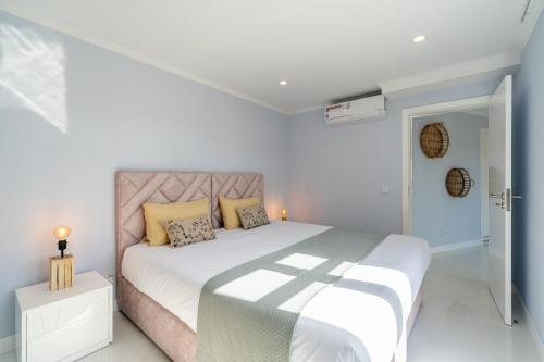a white bedroom with a large bed with yellow pillows at Stay In St. Catarina Park, by PAUSA H. Rentals in Funchal