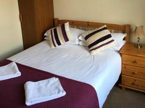 a bed with white sheets and pillows and a night stand at The Kings Arms in London
