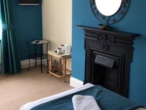 a blue room with a fireplace and a mirror at The Kings Arms in London