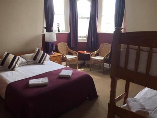 a hotel room with a bed and chairs and windows at The Kings Arms in London
