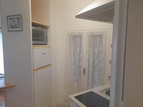 une cuisine blanche avec un évier et une fenêtre dans l'établissement Studio les thermes, à Amélie-les-Bains-Palalda