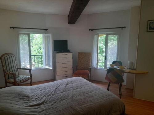 une chambre avec un lit et un bureau et deux fenêtres dans l'établissement Studio les thermes, à Amélie-les-Bains-Palalda