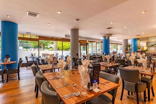 a restaurant with wooden tables and chairs at Britannia Leeds Bradford Airport in Bramhope