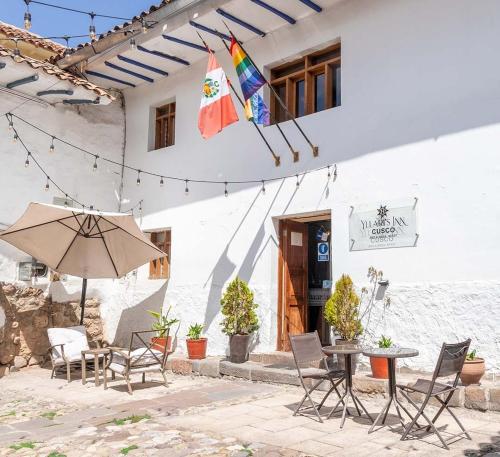 um pátio com cadeiras, uma mesa e um guarda-sol em Rumi's Inn em Cusco
