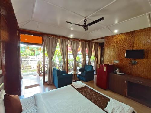 a bedroom with a bed and chairs and a television at Yerrata Resorts in Havelock Island