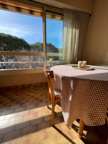 une table et des chaises dans une pièce avec une fenêtre dans l'établissement Appartement cosy sur le port proche des plages, à Hyères
