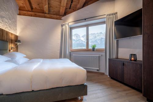 a bedroom with a large white bed and a window at Hotel Der Bär in Ellmau