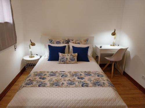 a bedroom with a bed with blue pillows and a desk at Buddies Charm House in Aveiro
