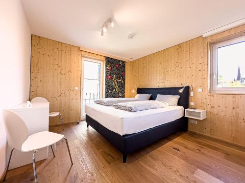 ein Schlafzimmer mit einem Bett in einem Zimmer mit Holzwänden in der Unterkunft Wolf & Schäfchen in Oberstaufen