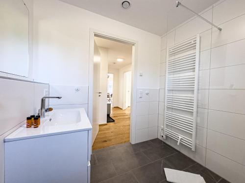 ein weißes Badezimmer mit Waschbecken und Spiegel in der Unterkunft Wolf & Schäfchen in Oberstaufen