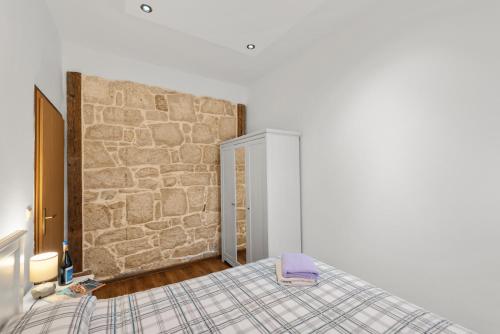 a bedroom with a bed and a stone wall at Alba Sanja i Teran in Funtana