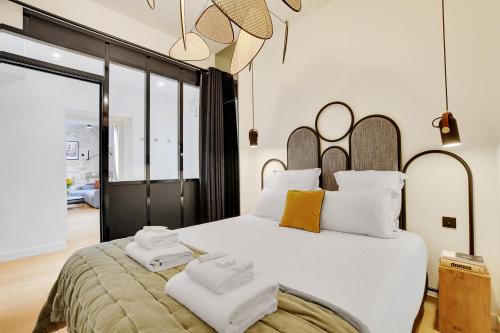 une chambre avec un grand lit blanc avec des serviettes dessus dans l'établissement SERENERS - Charming Serviced Apartments - Place des Vosges, à Paris