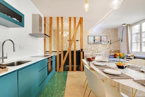 une cuisine avec des placards bleus et une table à manger dans l'établissement SERENERS - Charming Serviced Apartments - Place des Vosges, à Paris