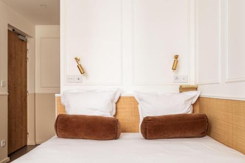 a bed with two pillows on top of it at Hôtel Maison Traversière in Paris