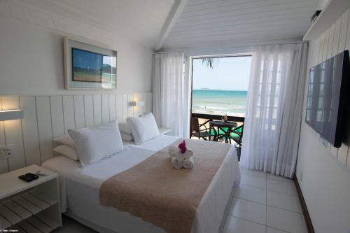 a bedroom with a bed with a view of the ocean at Chez Pitu Praia Hotel in Búzios