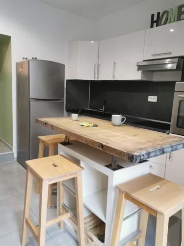 La cuisine est équipée d'un comptoir en bois avec tabourets et d'un réfrigérateur. dans l'établissement charmant appartement au cœur du village, à Claret