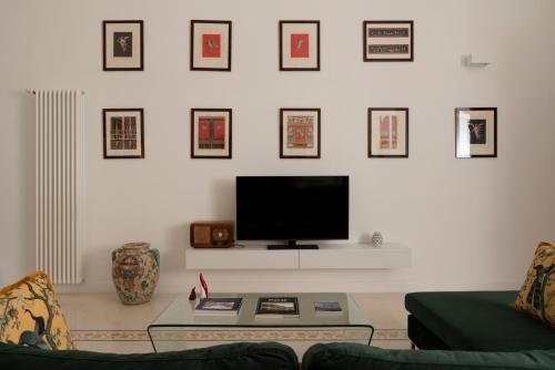 un soggiorno con TV a parete e immagini di A.RI.EL luxury apartment a Napoli