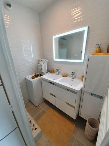 une salle de bain blanche avec un lavabo et un miroir dans l'établissement Cap au Large-Vue Mer Panoramique, à Cabourg