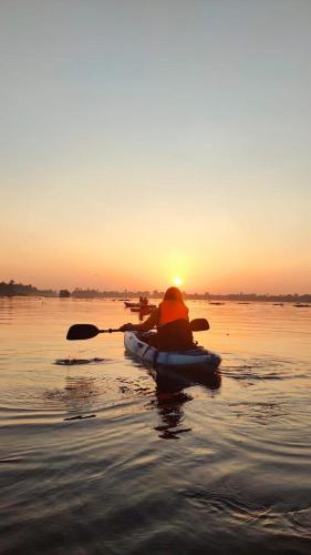 a person in a kayak on the water at sunset at SALT LIFE MARARI BEACH VILLA in Mararikulam