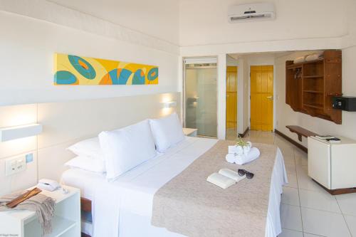 a bedroom with a large white bed with towels on it at Chez Pitu Praia Hotel in Búzios