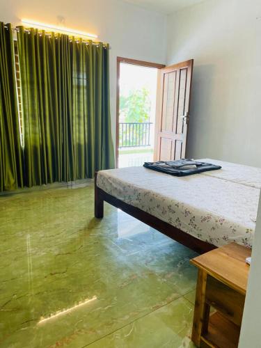 a bedroom with a bed and a window with green curtains at SALT LIFE MARARI BEACH VILLA in Mararikulam